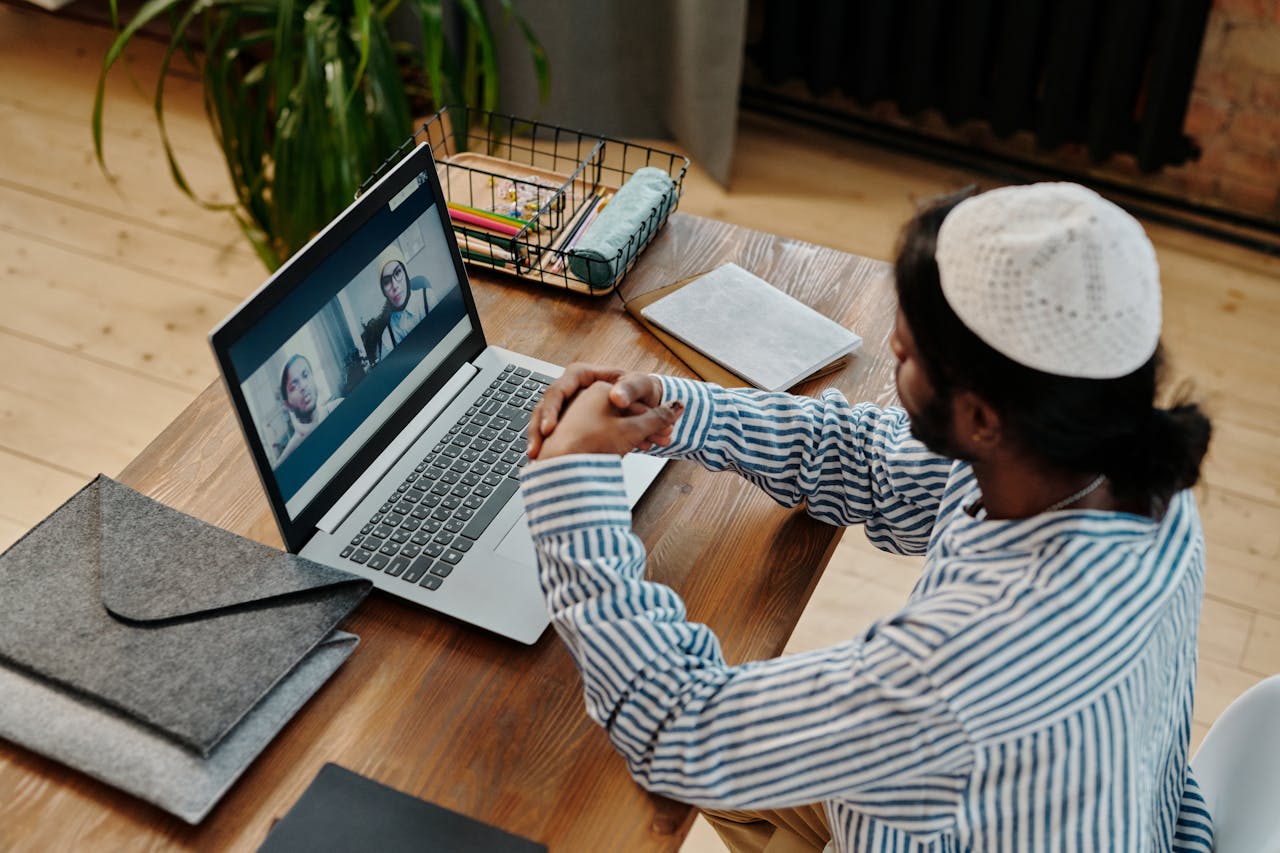 Man participating in video call from home office desk, focused and engaged.